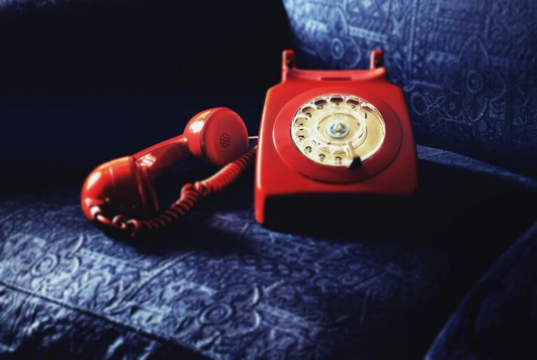 red rotary telephone on blue sofa